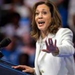 Kamala Harris habla en un mitin de campaña en Savannah, Georgia, el jueves 29 de agosto de 2024. Lleva un traje blanco y gesticula con una mano mientras está de pie detrás de un podio con micrófonos.