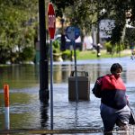 Una mujer camina por una calle inundada en South Daytona, Florida