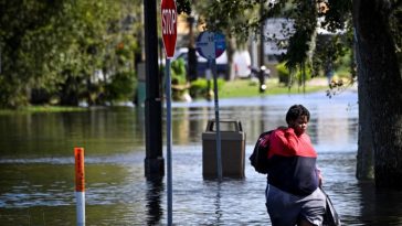 Una mujer camina por una calle inundada en South Daytona, Florida