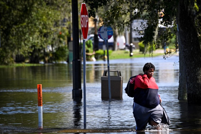 Una mujer camina por una calle inundada en South Daytona, Florida