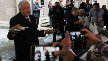 Un hombre que sostiene un plato de comida se enfrenta a una multitud de periodistas.