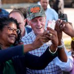 Bill Clinton, con una gorra con 'Harris Walz', se hace selfies con sus entusiastas seguidores sosteniendo teléfonos.