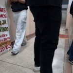 La gente camina junto a un cartel de una sesión grupal de Jugadores Anónimos en Sao Paulo, Brasil.