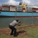 La gente observa cómo un buque portacontenedores transita por el Canal de Panamá.