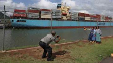 La gente observa cómo un buque portacontenedores transita por el Canal de Panamá.