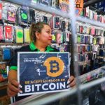 A vendor holds a sign reading ‘Bitcoin accepted’ at a store in San Salvador