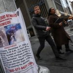 La gente pasa junto a un cartel que pide pistas sobre el asesinato de Brian Thompson en Nueva York