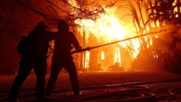 Los bomberos rocían agua sobre una casa en llamas mientras el incendio Eaton avanzaba por el área en Altadena, California, el miércoles.