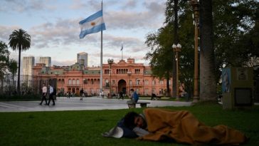 A homeless man sleeps at Plaza de Mayo square in front of Casa Rosada presidential palace in Buenos Aires