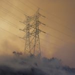 Smoke rises past a power line during the Palisades Fire