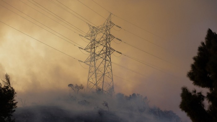 Smoke rises past a power line during the Palisades Fire