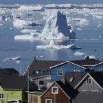 Icebergs seen from Greenland with houses in the foreground