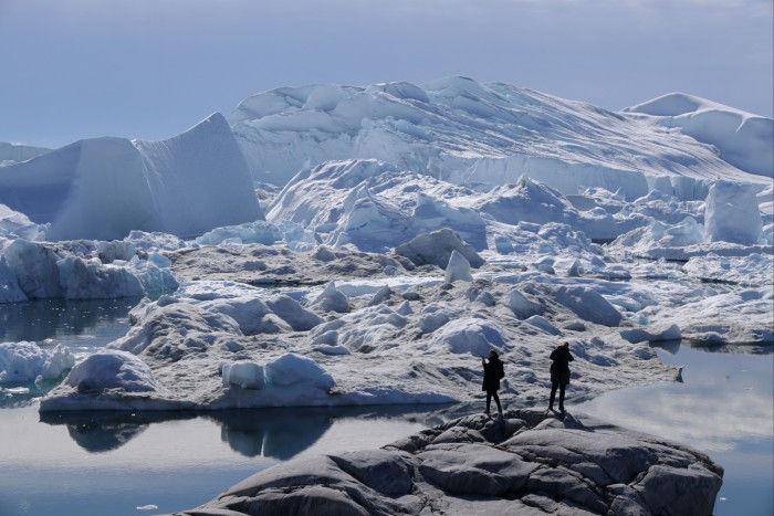 Visitantes observan el derretimiento de los icebergs en el fiordo helado de Ilulissat en julio de 2024 en Groenlandia