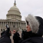 Person looks at her phone outside Capitol Hill