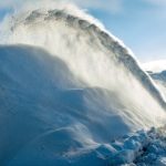 A snow ploughmoves along a road in Montreal, shooting up a spray of snow on to a huge bank of snow alongside the road