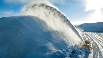 A snow ploughmoves along a road in Montreal, shooting up a spray of snow on to a huge bank of snow alongside the road