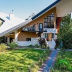 El exterior de una casa modernista con un techo muy inclinado y ventanas geométricas.