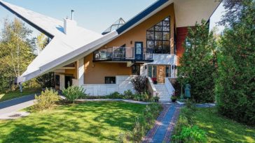 El exterior de una casa modernista con un techo muy inclinado y ventanas geométricas.