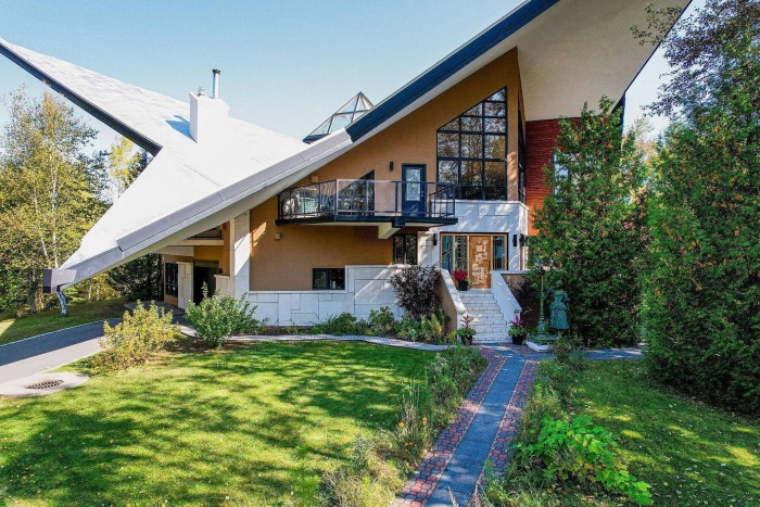 El exterior de una casa modernista con un techo muy inclinado y ventanas geométricas.