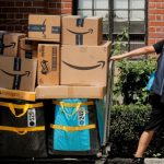 An Amazon delivery worker pulls a delivery cart full of packages in New York City