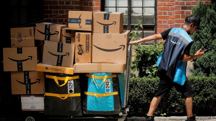 An Amazon delivery worker pulls a delivery cart full of packages in New York City