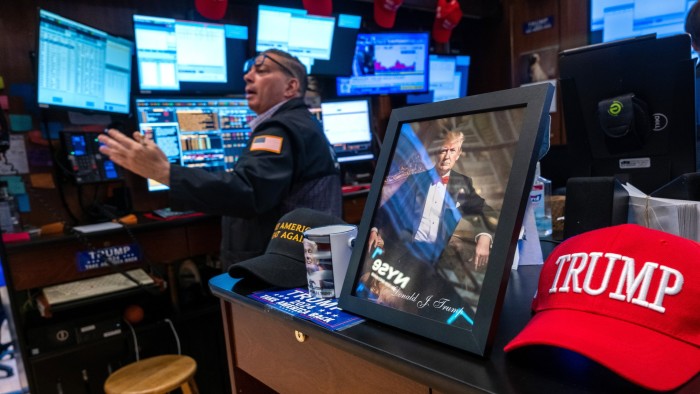 A picture of Donald Trump is displayed as traders work on the New York Stock Exchange