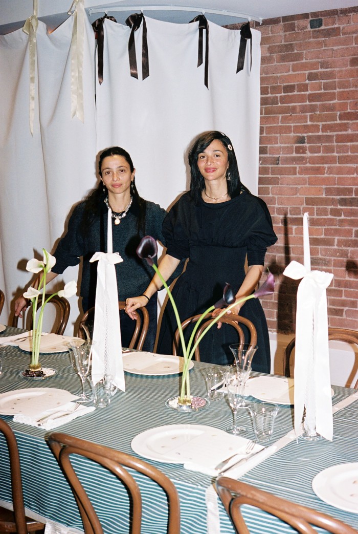 Laila Gohar (derecha) con su hermana Nadia parada junto a una mesa cubierta con un mantel azul verde